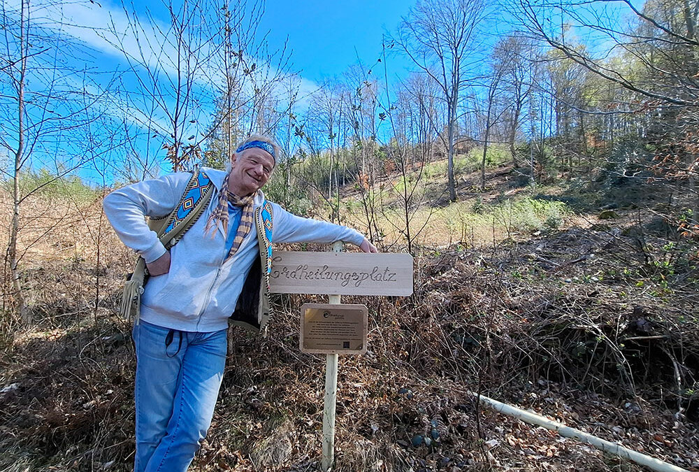 Tilo lehnt am Schild des Erdheilungsplatz Gummersbach Sonnenberg