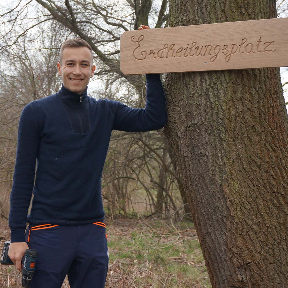 stiftung_erdheilungsplaetze_reisebericht_teaser Mitarbeiter Jan neben einem neuen angebrachten Schild auf einem Erdheilungsplatz