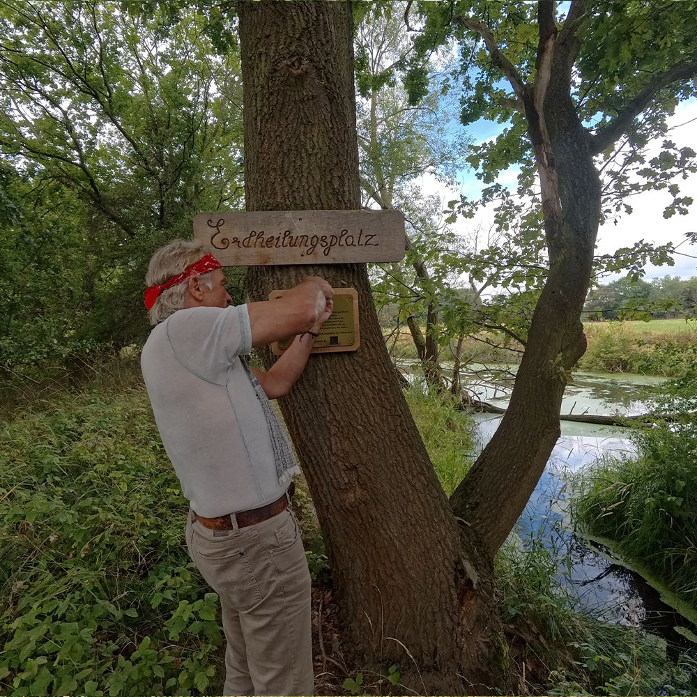 Gründer Tilo beim Anbringen der Schilder am Erdheilungsplatz Wallendorf Wald im Juli 2025